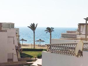 a view of a building and the ocean with palm trees at Concorde Royal Beach Village, Ras Sidr, South Sinai Villa 116 in Ras Sedr