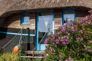 una hamaca frente a una casa con techo de paja y flores en LA CALOGE KASTELL DINN, en Crozon