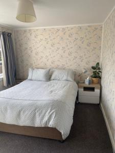 Un dormitorio con una cama con una pared de acento floral en Stay@10, en Blenheim