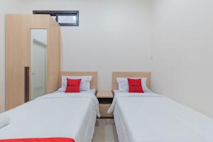 two beds with red pillows in a room at RedDoorz near CSB Mall Cirebon in Cirebon