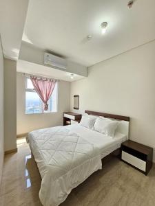 a bedroom with a large white bed and a window at Apartment Podomoro City Deli Medan in Medan