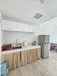 a kitchen with a counter with a sink and a refrigerator at Apartment Podomoro City Deli Medan in Medan