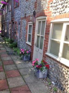 5 Museum Cottages في شيرينغهام: مبنى من الطوب مع الزهور الفخارية بجوار الباب