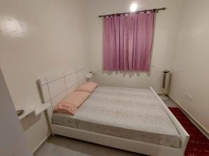 Dormitorio pequeño con cama y ventana rosa en Targa Flat, en Marrakech