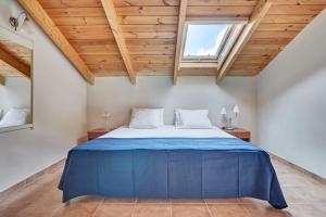 a blue bed in a room with wooden ceilings at Villa Eremia in Pastida