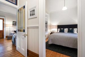 a white bedroom with a bed and a door at MARIGOLD COTTAGE Charming 1870s central Daylesford cottage in Daylesford