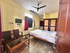 a bedroom with a bed and a chair and a ceiling fan at STAYMAKER Unnatha Residency in Manipal