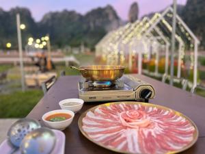 a table with a plate of food and a bowl of sauce at วันทน่า โฮมสเตย์ บ้านมุง เนินมะปราง in Ban Mung