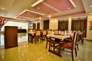 una sala da pranzo con tavoli e sedie in un ristorante di Harbour Hotels a Pallipuram