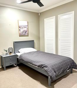 a bedroom with a bed and a ceiling fan at Luxury Holiday Home in Middle Ridge Toowoomba in Harristown