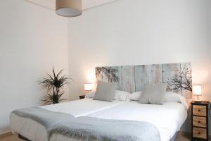 1 dormitorio con 1 cama blanca grande y cabecero en MonKeys Apartments Lumbreras Deluxe, en Sevilla
