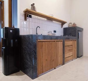 a kitchen with a black counter and a refrigerator at Casa Benna - Salatiga in Salatiga