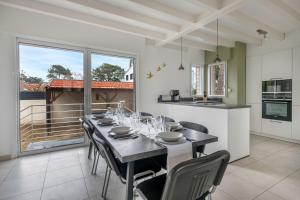 a dining room with a table and chairs and a kitchen at Maison rénovée pour 8 - 200m Tharon plage in Tharon-Plage
