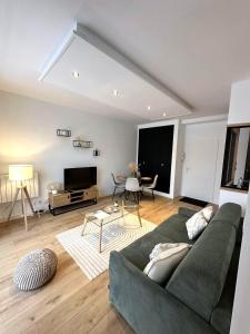 a living room with a green couch and a tv at L’esplanade du lac in Gérardmer