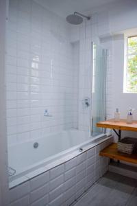 La salle de bains blanche est pourvue d'une baignoire et d'une fenêtre. dans l'établissement 2 Bedroom Apartment with Modern Finishes Hill Tud Stays, à Pietermaritzburg