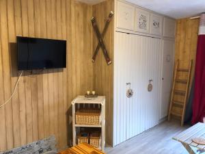 studio tout confort au pied des pistes du lioran في Laveissière: غرفة معيشة مع تلفزيون على الحائط وباب
