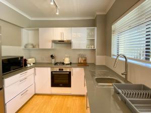 una cocina con armarios blancos y fregadero en Sundrenched 2 bed 2 bath apartment + sea views en Ciudad del Cabo