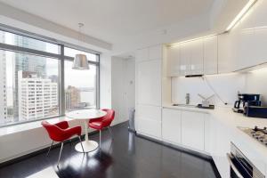 a white kitchen with red chairs and a table at Financial District 1br w WD gym elevator NYC-1369 in New York