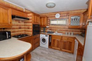 a kitchen with wooden cabinets and a washer and dryer at The Den in Sheringham