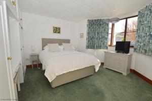 a white bedroom with a bed and a television at The Den in Sheringham