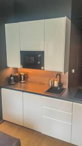 een keuken met witte kasten en een zwarte magnetron bij Biała Perła Czarna Góra Resort Apartament 102 in Siena