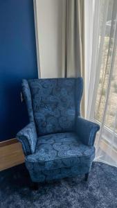 a blue chair in a room with a window at Biała Perła Czarna Góra Resort Apartament 102 in Sienna