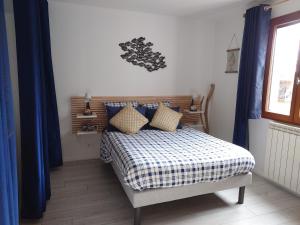 a bedroom with a bed with blue curtains and a window at Cigaléo, Chambre d'hôtes dans le Var in Carnoules