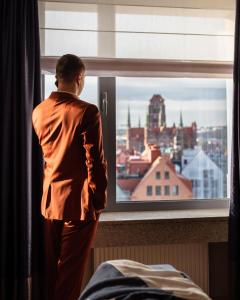 un hombre mirando por una ventana a una ciudad en Hotel Marina Club Old Town View, en Gdansk