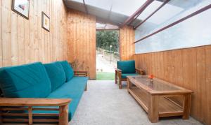 a living room with a blue couch and a table at Treebo Trend Daak Bangla Retreat With Mountain View in Shimla