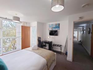 - une chambre avec un lit, un bureau et une fenêtre dans l'établissement Three Bed Serviced Apartment by London ExCeL, à Londres