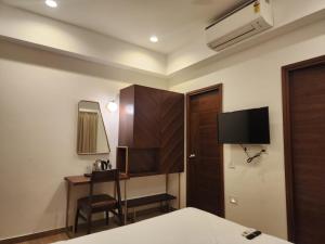 a bedroom with a bed and a desk and a tv at Flora Embassy in Chennai