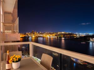 un balcón con vistas al agua por la noche en Exceptional Tigne Seafront Apartments by Shortletsmalta, en Sliema