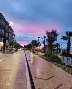 an empty street with palm trees and a sunset at Residence Rimini Relax in Rimini
