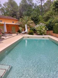 uma piscina com água azul em frente a uma casa em La Bastine em Lorgues