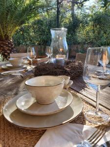 uma mesa com uma taça, pratos e copos de vinho em La Bastine em Lorgues