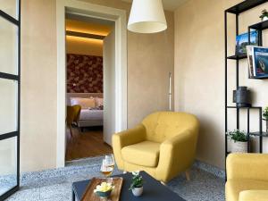 a living room with a yellow chair and a bedroom at Casa Rampolina in Stresa