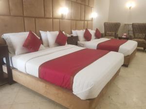 2 Betten in einem Hotelzimmer in Rot und Weiß in der Unterkunft Shelton Accommodator in Peschawar
