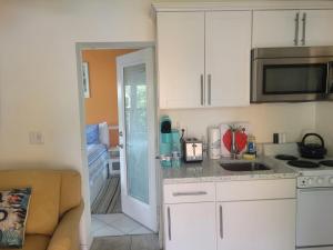 ~ Cozy In-law Apartment Close to Siesta Key ~ في ساراسوتا: مطبخ صغير مع دواليب بيضاء ومغسلة