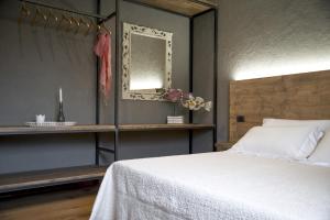 Il Giardino di Ortensia B&B في بيينْتينا: غرفة نوم بسرير ابيض ومرآة