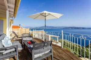 a balcony with chairs and an umbrella and the water at INFINITY BLUE in Agní