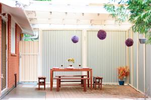 a table and benches on a patio with purple balls at Modern Cozy Retreat-3Bedroom, Full Kitchen, Coffee Machine, Cot, Pets allowed-Fully Fenced,FreeWifi, Netflix, 2TV in Campbelltown