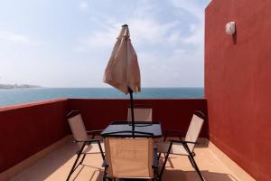 una mesa con sillas y una sombrilla en el balcón en Casa completa triplex & parking by Gades Gestión, en Cádiz