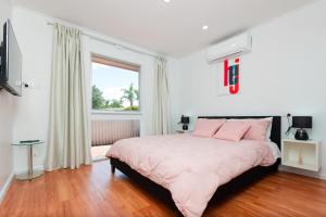 Un dormitorio con una cama con almohadas rosas y una ventana en Modern Cozy Retreat-3Bedroom, Full Kitchen, Coffee Machine, Cot, Pets allowed-Fully Fenced,FreeWifi, Netflix, 2TV, en Campbelltown