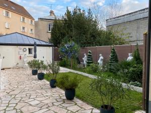 einen Garten mit Topfpflanzen und einem Zaun in der Unterkunft Paris City Flat 51M carrée Appt 105 F2 Grd Paris in Alfortville