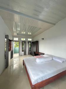 um quarto com uma grande cama branca e uma mesa em Caesarea Villa em Berastagi
