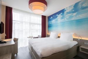 - une chambre avec un grand lit orné d'une peinture murale dans l'établissement Ramada The Hague Scheveningen, à Scheveningen