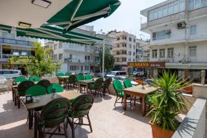 an outdoor patio with tables and green chairs at Hikmethan Otel in Kusadası