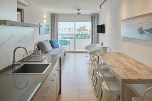 una cucina con lavandino e bancone con tavolo di Playa Bella Apartments a Baia di Sant'Antoni