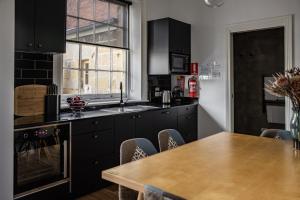 eine Küche mit schwarzen Schränken und einem Holztisch in der Unterkunft Sanctum Boutique Apartments in Hobart