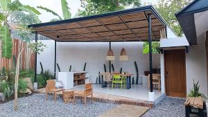 un patio con pérgola de madera, mesa y sillas en Casa Benna - Salatiga, en Salatiga